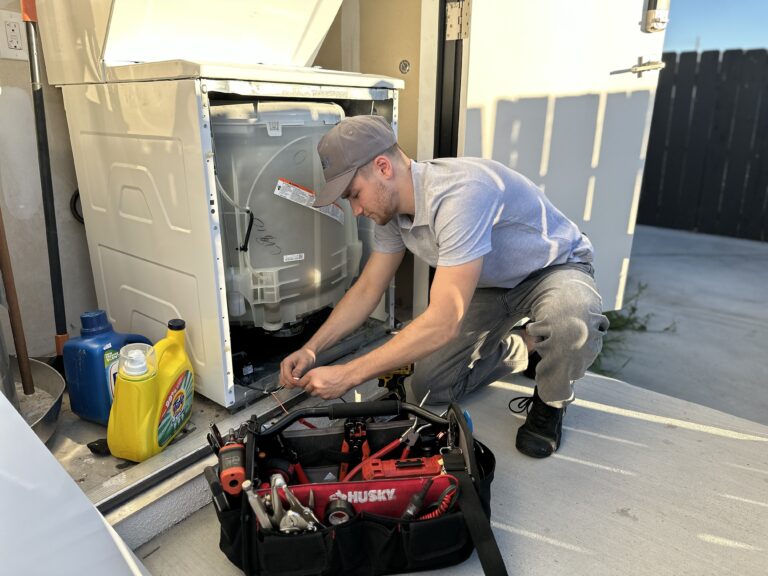 Technician repairing a residential washing machine in San Diego County